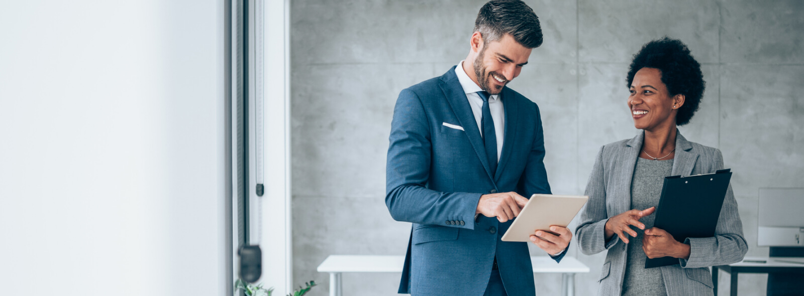 Businesswoman and businessman talking while looking at tablet device