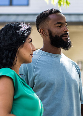 Man and Woman standing outside a home contemplating