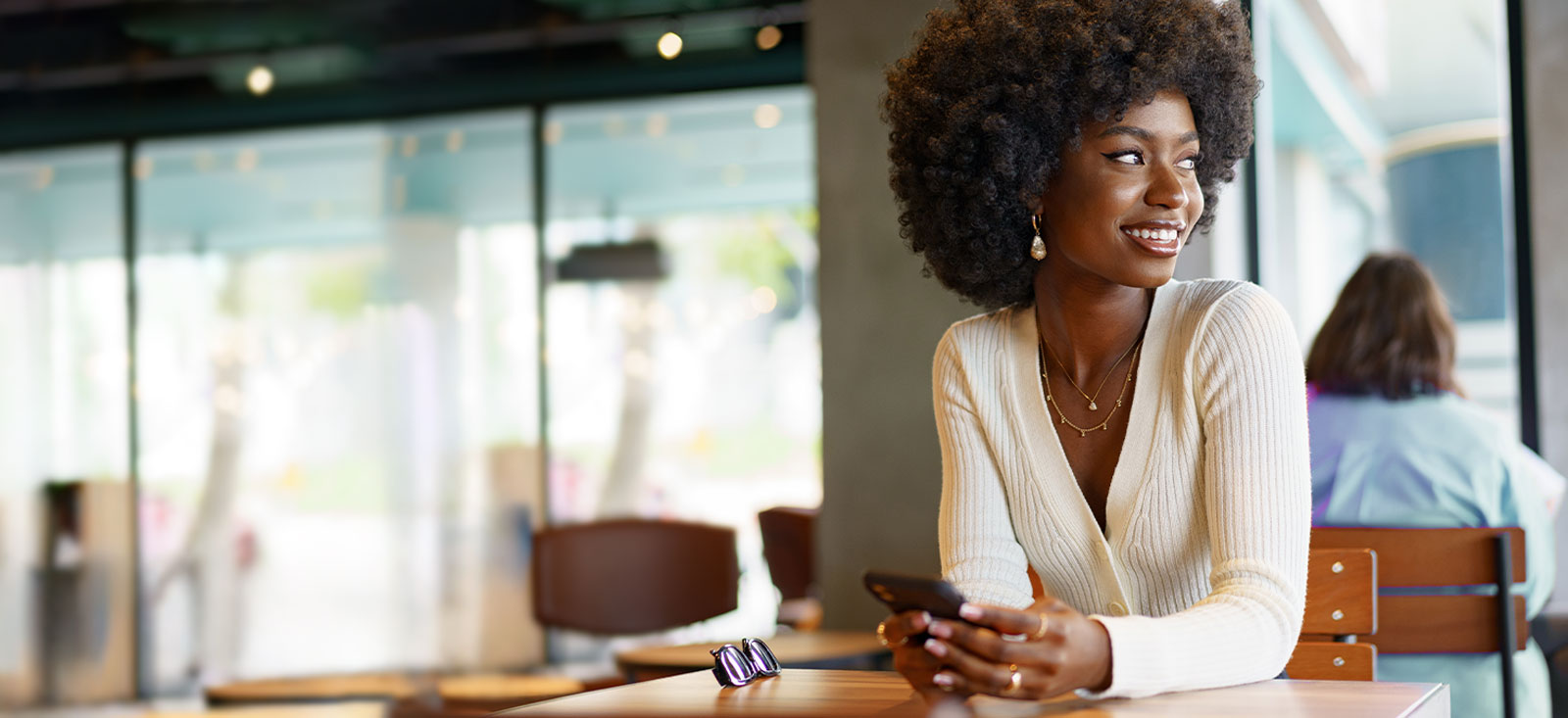 Young woman sitting in a restaurant with her cell phone.