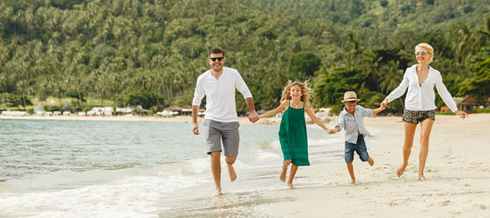 Family running down a sandy beach