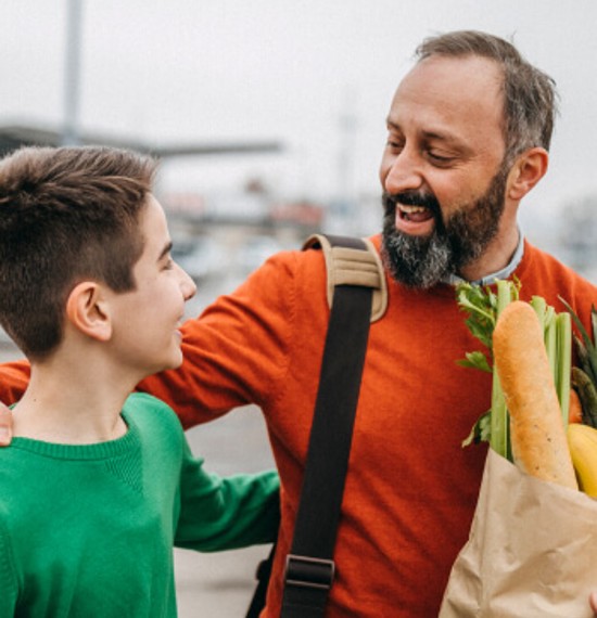 Father and son leaving the store with a bag of groceries