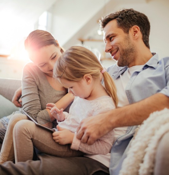 Family sitting on the couch together while playing on a tablet