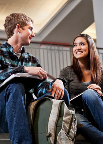 Two college students sitting with their books while smiling