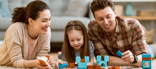 Parents playing with building blocks with their young daughter