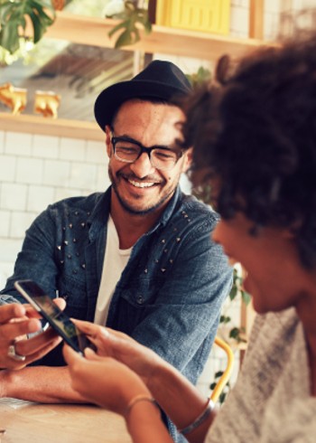 Man laughing while showing a friend something on his phone