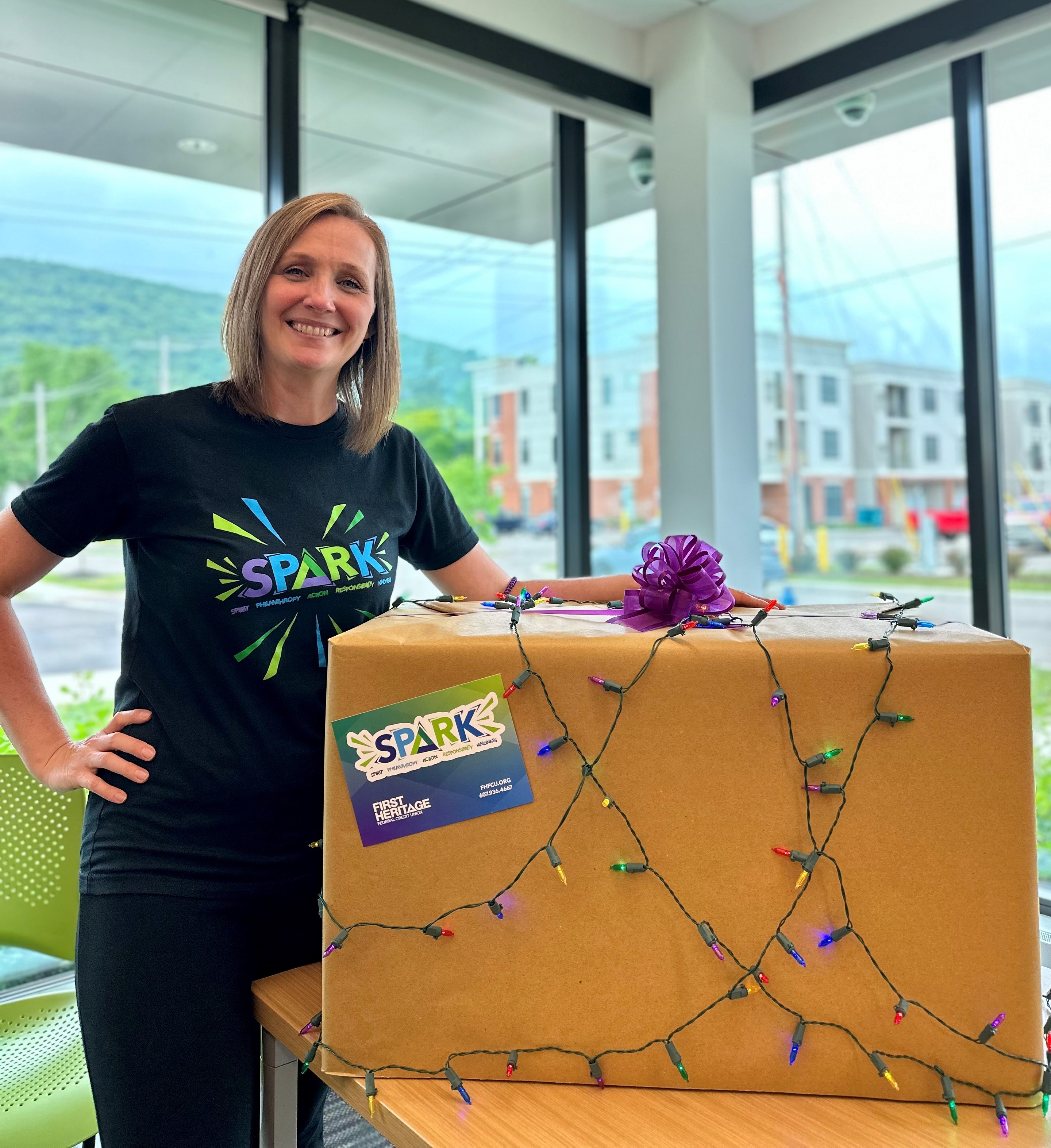 Christy standing with a box of toy donations for Christmas in July.